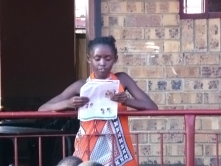 Sinethemba Nkosi reading in front of 1150 learners